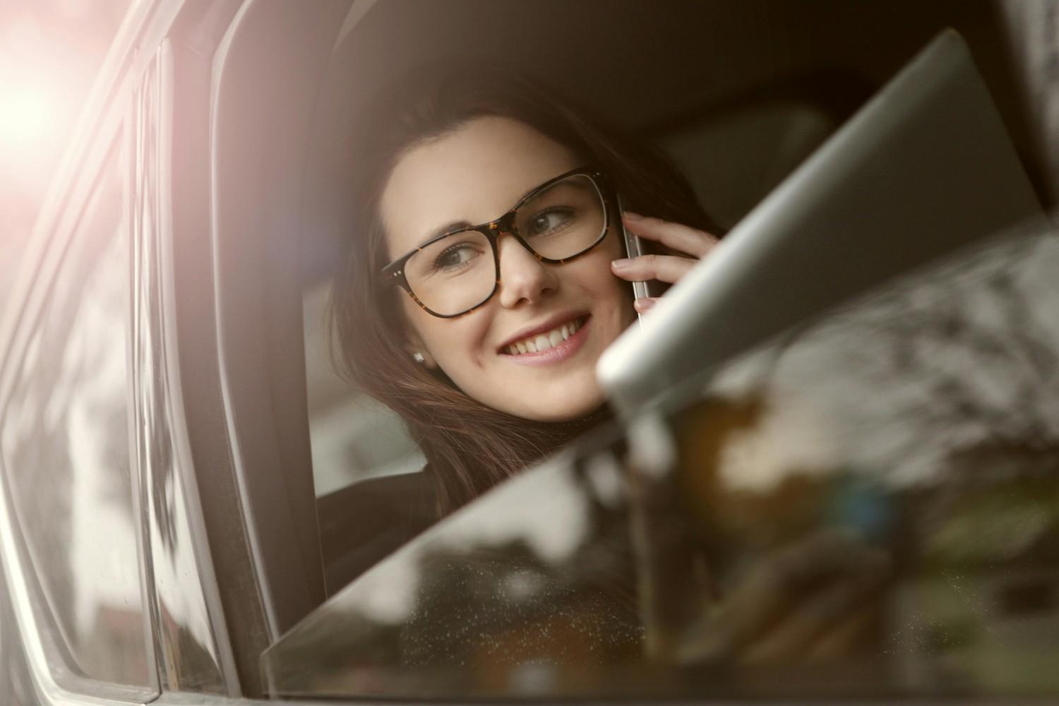 A professional woman smiling while sitting in a modern car, representing safety and insurance coverage